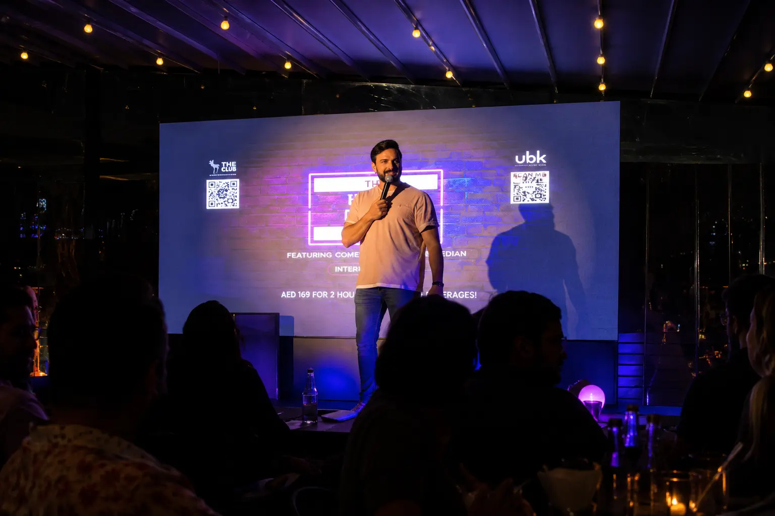 Professional corporate comedian entertaining guests during a live comedy show at a Dubai corporate event venue.