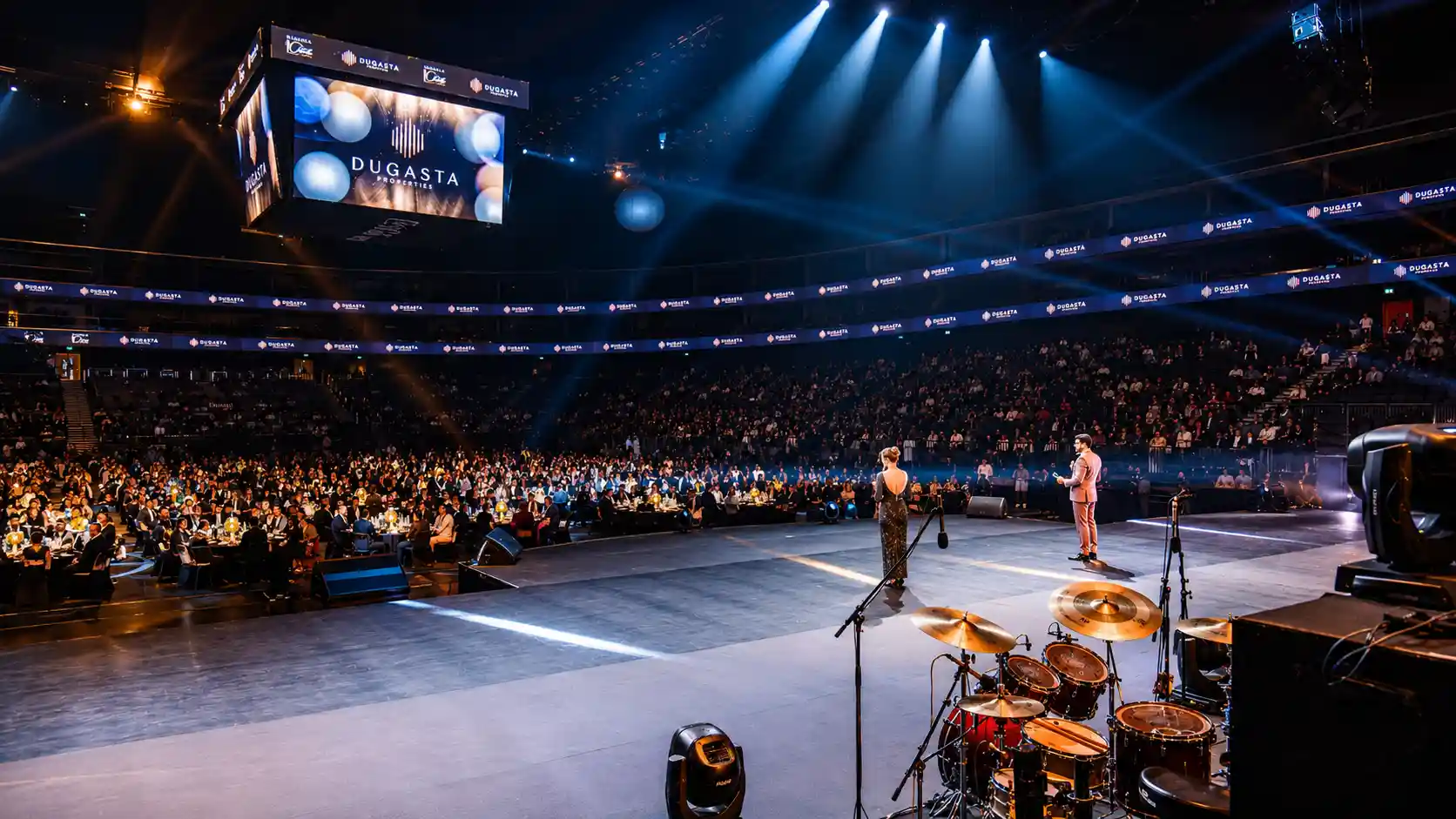 Dugasta Properties corporate event in Dubai with professional MCs hosting on stage in front of a large audience with live event production and entertainment.