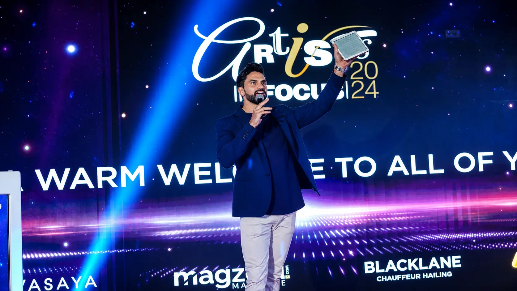 Professional MC in Dubai hosting a corporate conference with audience engagement and stage lighting.