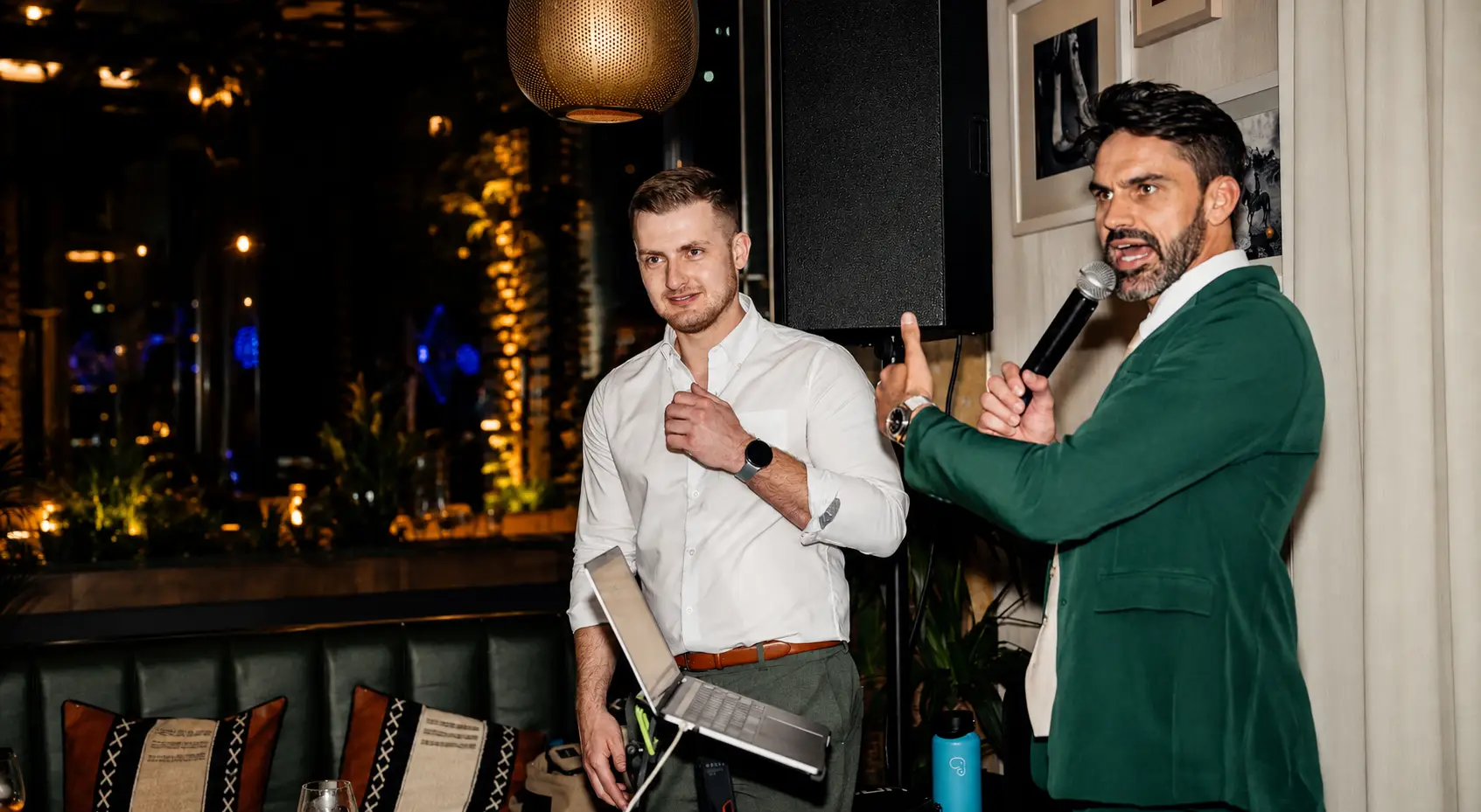  Professional Master of Ceremonies speaking during a live corporate networking event in Dubai, coordinating with the event team while addressing guests with a wireless microphone.