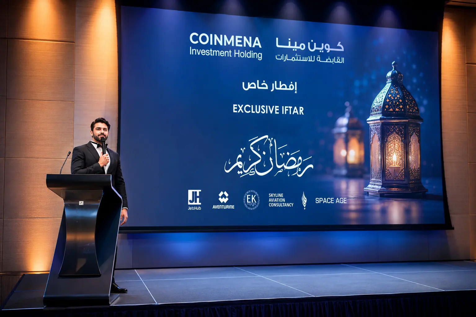 Professional MC in Dubai hosting an exclusive corporate Iftar event, speaking from a podium on stage in front of a large branded presentation screen displaying event sponsors and Ramadan-themed visuals.